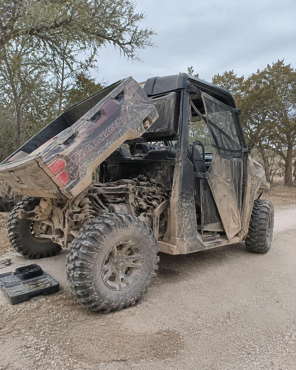 UTV bed raised for on-site engine service on a ranch road.